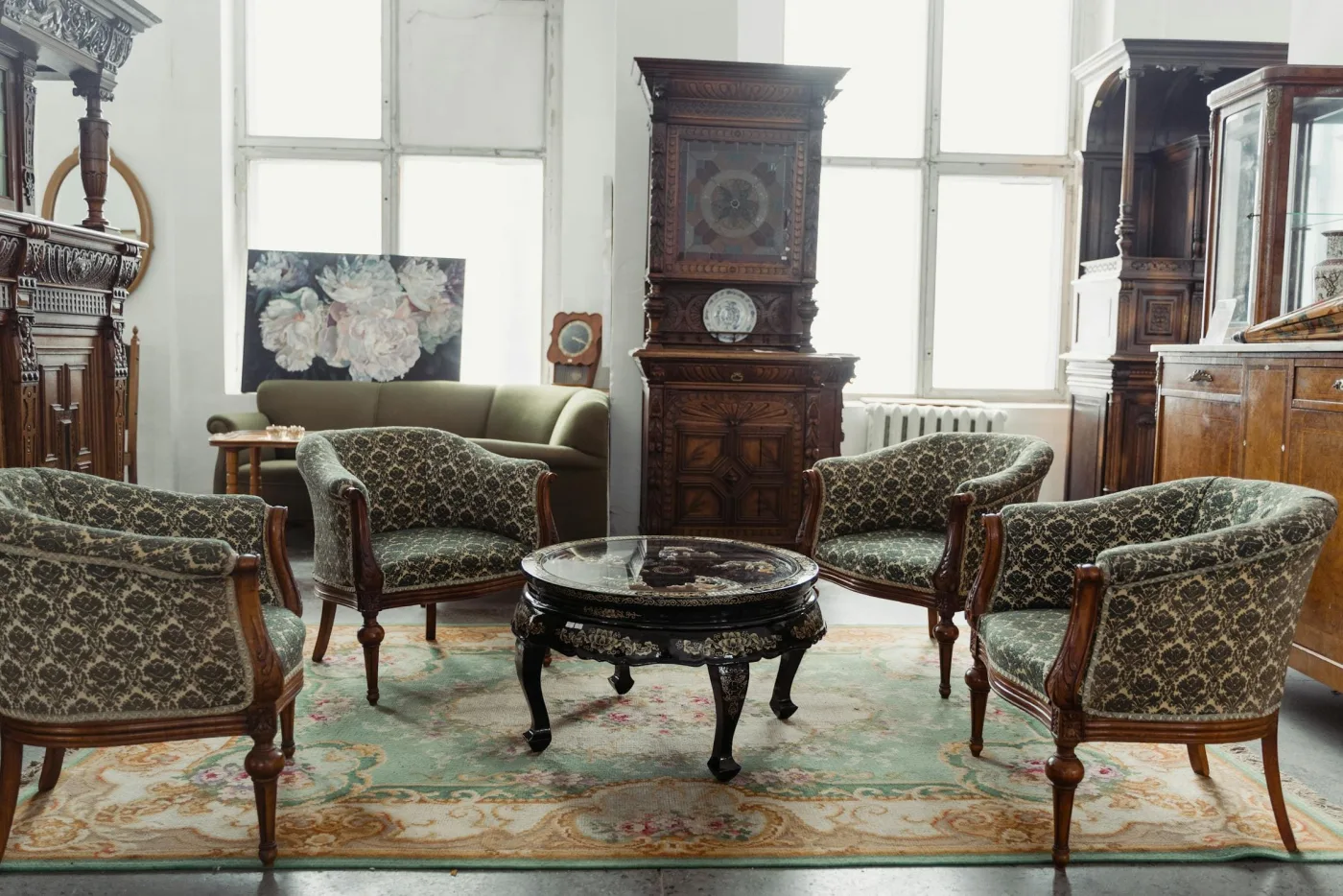 Fauteuils crapauds tapissés de damas autour d'une table basse laquée, devant des buffets en chêne sculpté